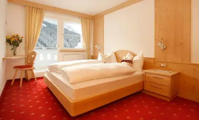 a bedroom with a bed and a window at Apartments Antines in Selva di Val Gardena