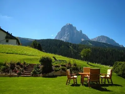 a group of chairs and a table in the grass at Apartments Antines in Selva di Val Gardena