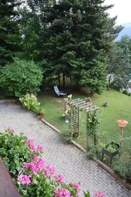 a garden with a table and some flowers and trees at Casa Corgol con vista lago e montagne in Predaia