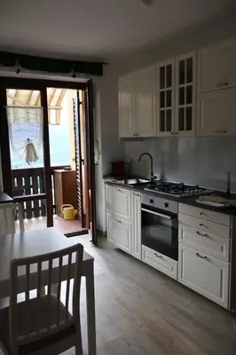 a kitchen with white cabinets and a stove and a table at Casa Corgol con vista lago e montagne in Predaia