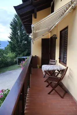 a porch of a house with a table and a chair at Casa Corgol con vista lago e montagne in Predaia