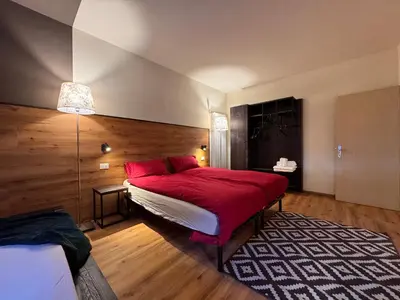 a bedroom with a red bed and a rug at Villa Ginestra - 1 in Moena