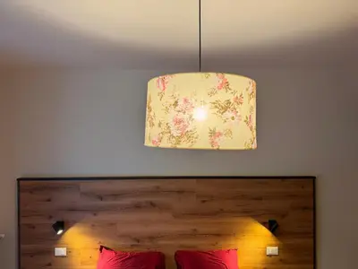 a pendant light hanging above a bed with red pillows at Villa Ginestra - 1 in Moena