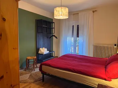 a bedroom with a red bed and a chandelier at Villa Ginestra - 1 in Moena