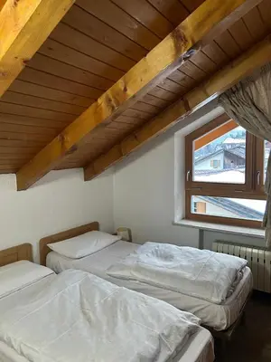 a bedroom with a bed and two chairs and a table at Appartamenti Decrestina in Campitello di Fassa
