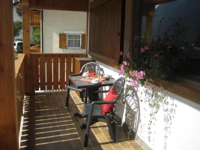 a white umbrella sitting on a table with two chairs at Appartamenti Decrestina in Campitello di Fassa