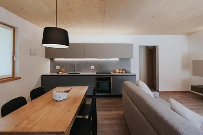 a kitchen and dining room with a wooden table and a couch at Falcade Lodge in Falcade