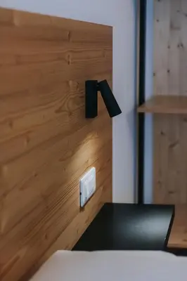 a bedroom with a wooden wall with a light switch at Falcade Lodge in Falcade