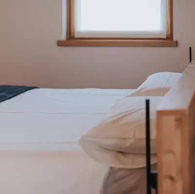 a bedroom with a white bed with a window at Falcade Lodge in Falcade