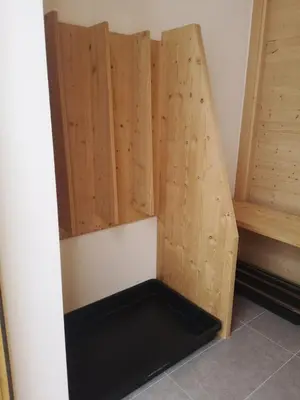 a room with a wooden wall with a black shelf at Falcade Lodge in Falcade