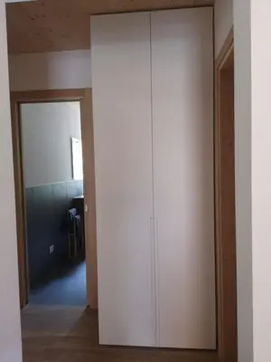 a large white cabinet in a room with a door at Falcade Lodge in Falcade