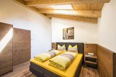 a bedroom with a yellow bed with pillows on it at Eggbauer Panorama Apartments in Cermes
