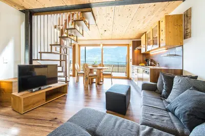 a living room with a couch and a tv and a kitchen at Eggbauer Panorama Apartments in Cermes