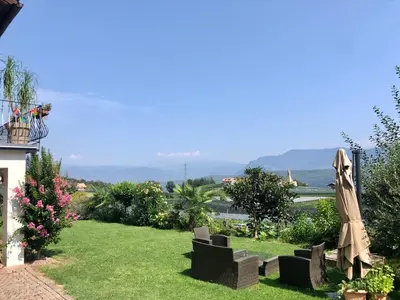 a garden with chairs and an umbrella on the grass at Weitblick Apartment mit Garten in Castelvecchio