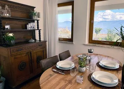 a wooden table with chairs and plates and a window at Weitblick Apartment mit Garten in Castelvecchio