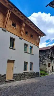 a white house with a wooden roof at Staguda 59 in Sottoguda