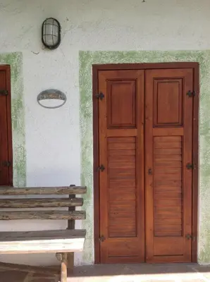 a wooden door and a bench next to a building at Baita cavalese giardino esclusivo in Cavalese