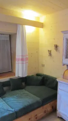 a living room with a green couch and a window at Baita cavalese giardino esclusivo in Cavalese