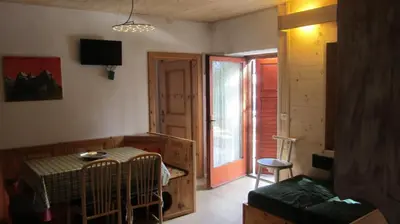 a room with a crib and a table and a door at Baita cavalese giardino esclusivo in Cavalese