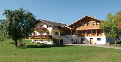 a town in a green field with mountains in the background at Kachlerhof in Castelrotto