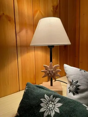 a lamp sitting on a table next to a bed at Stella Alpina San Martino di Castrozza vista Pale in San Martino di Castrozza