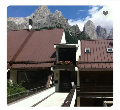 a house with a balcony with mountains in the background at Stella Alpina San Martino di Castrozza vista Pale in San Martino di Castrozza