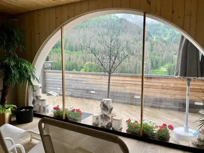 an arched window in a room with a table with flowers at Wellness Residence Panorama - check-in at Olympia Hotel in Arabba