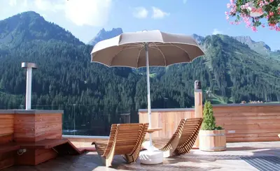 a patio with a table and chairs and an umbrella at Wellness Residence Panorama - check-in at Olympia Hotel in Arabba