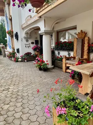 a building with a bench and flowers in front of it at Wellness Residence Panorama - check-in at Olympia Hotel in Arabba