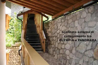 a stone wall with a staircase in front of a building at Wellness Residence Panorama - check-in at Olympia Hotel in Arabba