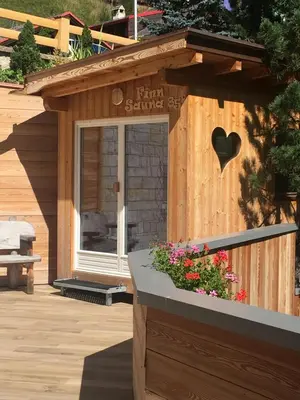 a wooden building with a heart sign on it at Wellness Residence Panorama - check-in at Olympia Hotel in Arabba