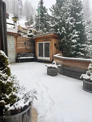 a snow covered yard in front of a cabin at Wellness Residence Panorama - check-in at Olympia Hotel in Arabba