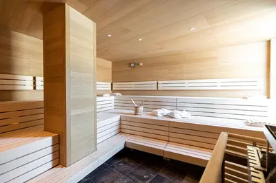a sauna with wooden walls and benches in a room at Hotel Patriarch in Tirolo