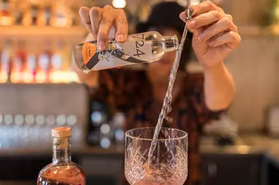 a woman is pouring a drink into a glass at Hotel Patriarch in Tirolo