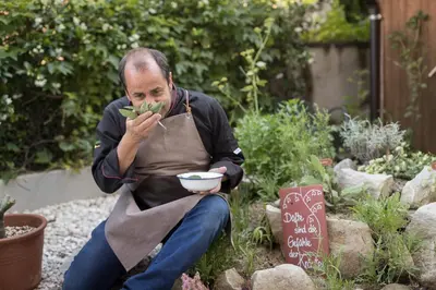 a man sitting in a garden eating a bowl of plants at Hotel Patriarch in Tirolo