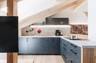 a kitchen with gray cabinets and a wooden floor at Flaschtal-Hof in Nova Ponente
