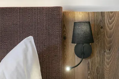 a lamp on a wall next to a bed at Schattmair Hof in Tirolo
