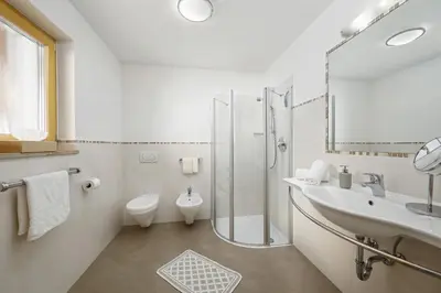a white bathroom with a shower and a sink at Schattmair Hof in Tirolo