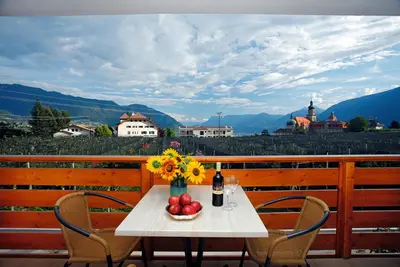 a table with a vase of flowers and a bottle of wine at Schattmair Hof in Tirolo