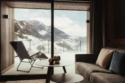 a living room with a couch and a large window at Luxury Chalet P in Ortisei