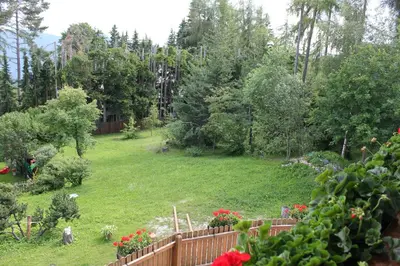 a backyard with a fence and a yard with flowers at Residence Lärchenhäusl in Soprabolzano