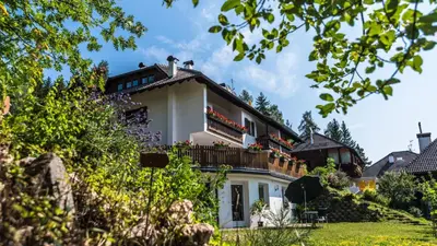 a white house with a balcony on a hill at Residence Lärchenhäusl in Soprabolzano
