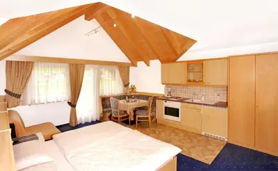 a kitchen with a bed and a table in a room at Garni La Majon in Selva di Val Gardena