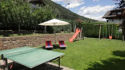 a playground with a table and chairs and an umbrella at Ferienwohnungen Haus Christine in Rifiano