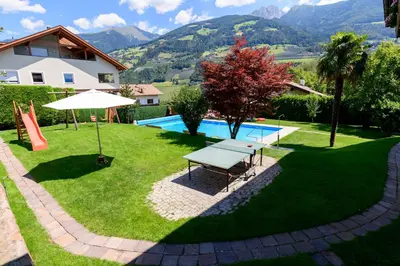 a backyard with a picnic table and an umbrella at Ferienwohnungen Haus Christine in Rifiano