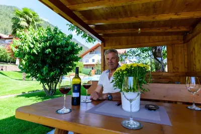 a man sitting at a table with two glasses of wine at Ferienwohnungen Haus Christine in Rifiano