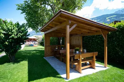 a wooden gazebo with a table in the grass at Ferienwohnungen Haus Christine in Rifiano