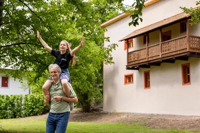 a girl on the back of a man in front of a house at Haus Himmelfahrt in Soprabolzano