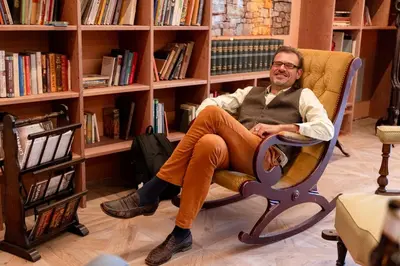 a man sitting in a chair in a library at Haus Himmelfahrt in Soprabolzano