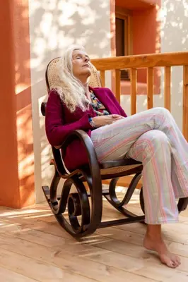a woman sitting in a rocking chair on a porch at Haus Himmelfahrt in Soprabolzano